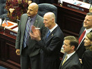 Gov. Rick Scott, standing with Rep. Ritch Workman, left, applauds as a motor vehicle tax cut passes the House on Thursday. Photo by Bruce Ritchie